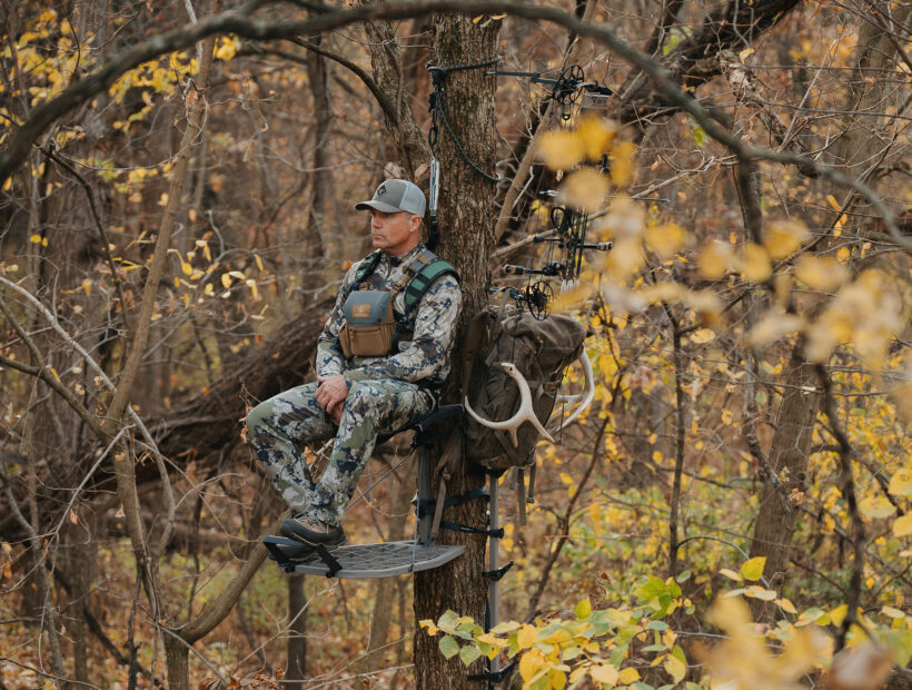 A man sitting in a tree stand wearing Malta hunting gear